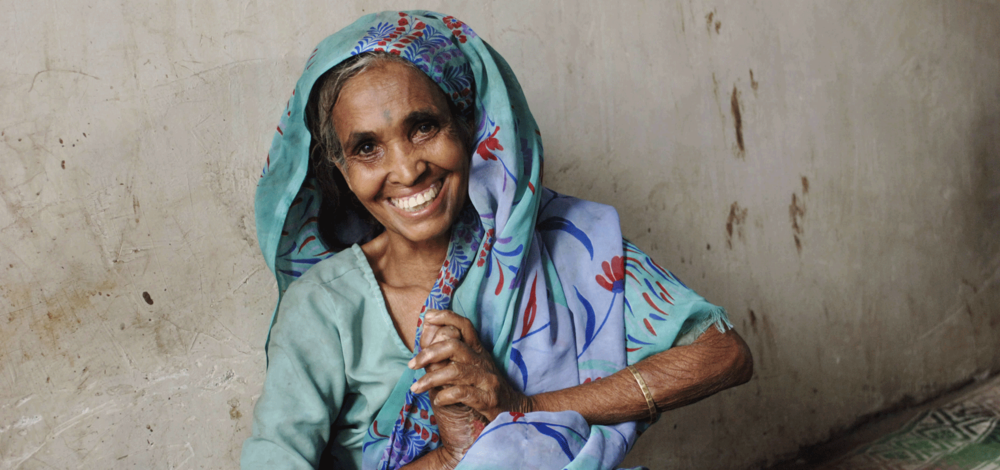 Leprosy mission - woman sitting against wall, smiling